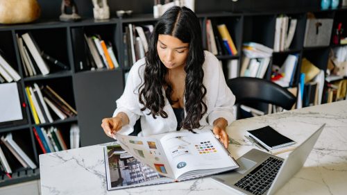 Foto de joven estudiando con un libro y laptop
