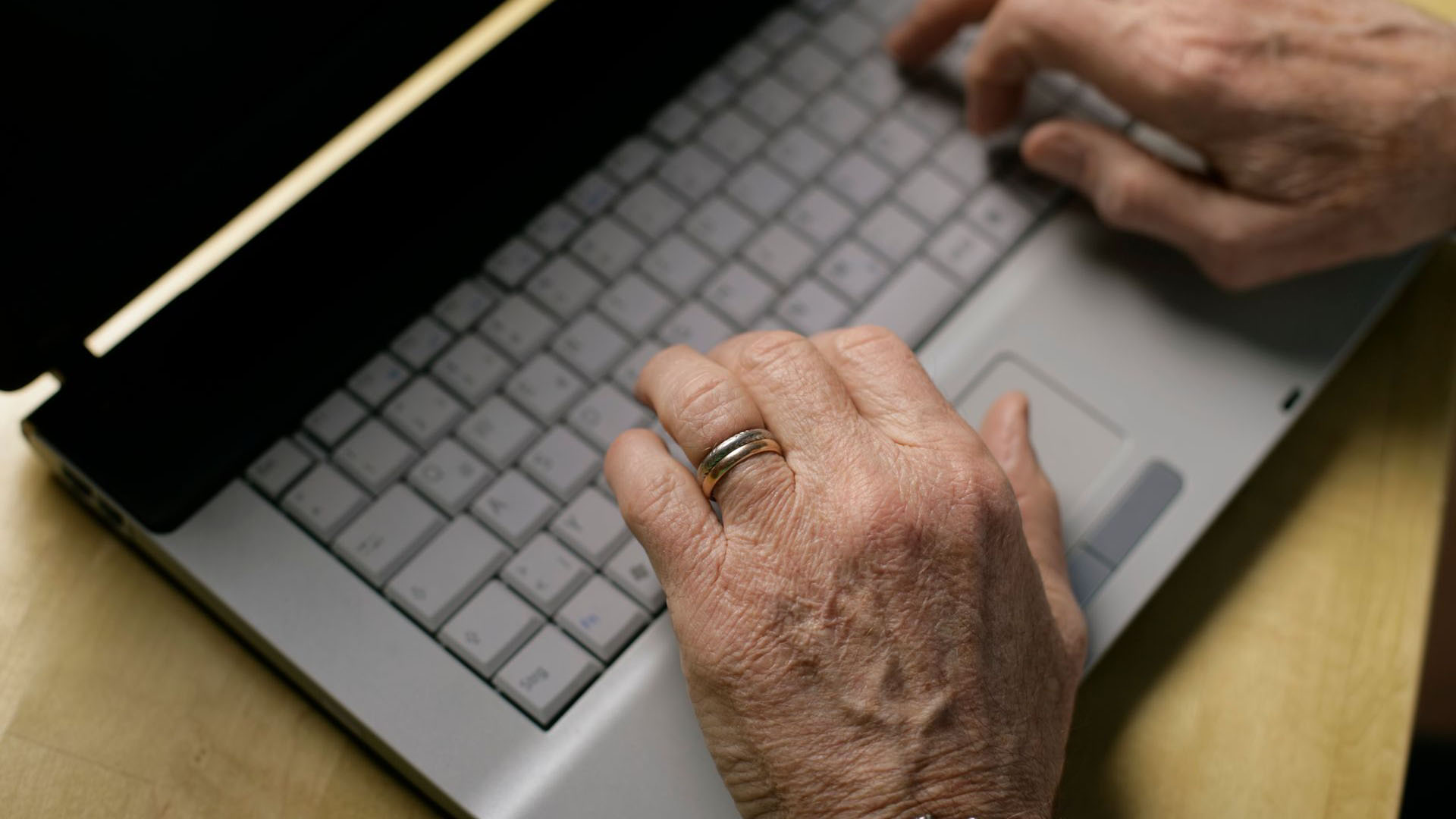 Foto de manos de una persona mayor usando una laptop