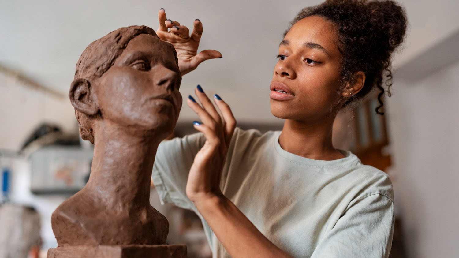 Foto de una joven esculpiendo un busto.