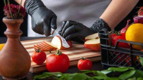 Foto de una persona con guantes cortando una manzana